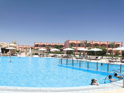 Gran piscina exterior con tumbonas y sombrillas frente a los edificios del hotel bajo un cielo despejado.
