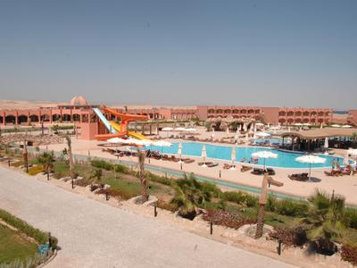 Gran resort con piscina, tobogán de agua y tumbonas bajo cielo despejado.