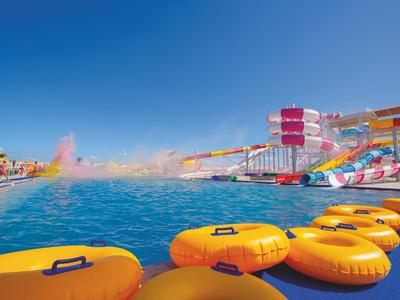 Toboggans aquatiques colorés et anneaux jaunes dans un parc aquatique sous un ciel dégagé.