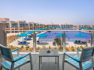 Terrazza con vista su una grande piscina e sedie sotto ombrelloni.