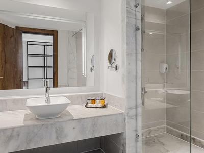 Bagno moderno con lavabo, specchio e doccia in vetro.