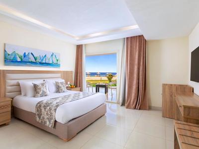 Modernes Hotelzimmer mit großem Bett, Balkon und Meerblick bei Tageslicht.