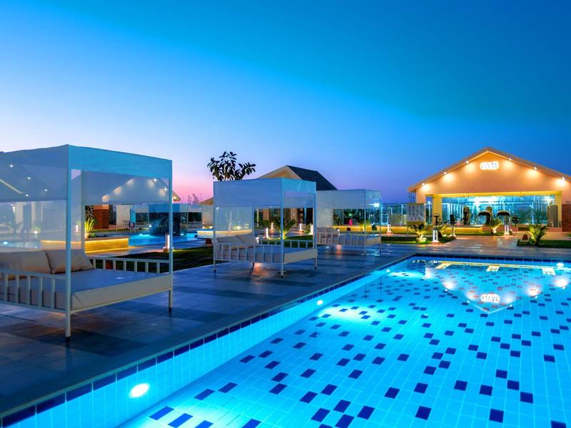 Piscina illuminata e aree relax moderne in un hotel al crepuscolo.