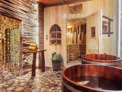 Rustieke wellnessruimte met houten badkuipen, sauna en natuurstenen vloer.