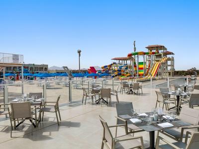 Leeg terras met tafels en stoelen voor een waterpark met glijbanen onder een heldere hemel