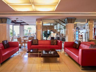 Hotel-Lounge mit roten Ledersofas, einem Glastisch und großen Fenstern im Hintergrund.