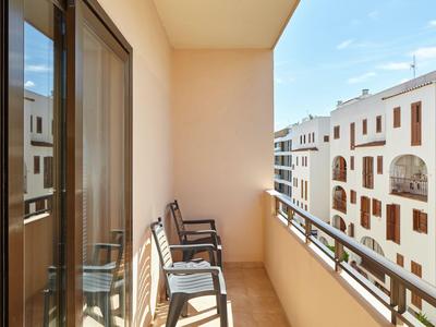 Balkon mit Stühlen und Blick auf umliegende weiße Gebäude in einer Hotelanlage.