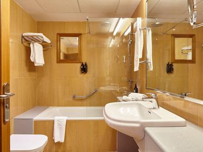 Helles Badezimmer mit Badewanne, Waschbecken und großen Spiegeln in Holzakzenten.