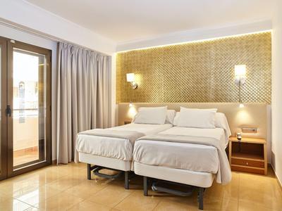 Modern eingerichtetes Hotelzimmer mit zwei Einzelbetten und großem Fenster mit Gardinen.