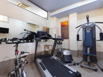 Kleiner Fitnessraum mit Laufband, Heimtrainer und Mehrzweckkraftgerät in hellem Raum.