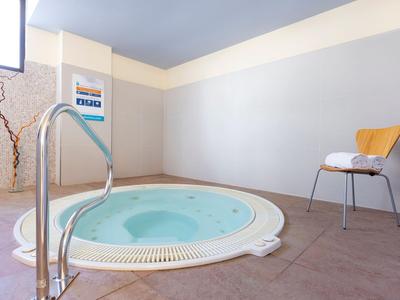 Moderner Whirlpool in einem hellen, minimalistischen Raum mit Stuhl und Handtuch.