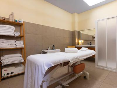 Heller Wellnessraum mit Massageliege, Handtüchern und entspannter Atmosphäre.