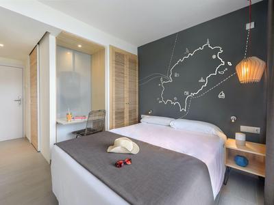 Moderní hotelový pokoj s manželskou postelí, mapou na stěně, psacím stolem a jemným osvětlením.