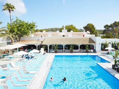 Gran área de piscina de hotel con tumbonas y sombrillas bajo un cielo soleado.