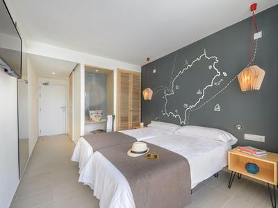 Moderní hotelový pokoj s dvojlůžky, dřevěnými nočními stolky a hvězdnou soustavou na zdi.