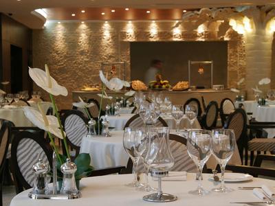 Restaurant élégant avec tables dressées, fleurs blanches et mur en pierre moderne.