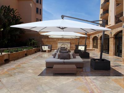 Moderner Lounge-Bereich mit Sonnenschirm auf einer Hotelterrasse bei klarem Himmel