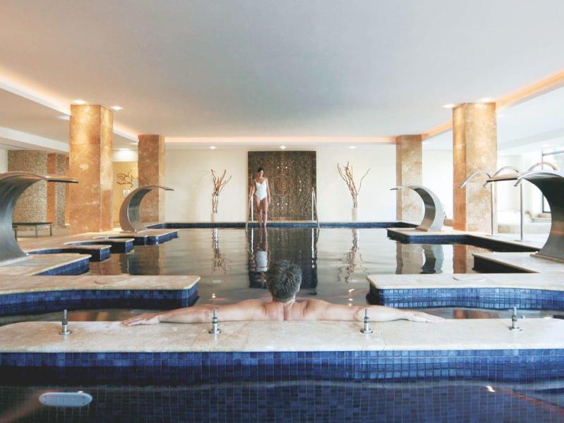 Piscine intérieure moderne avec fontaines dans un spa hôtelier de luxe.