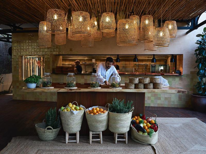 Étal de marché avec paniers et fruits, décoré de lampes suspendues dans un espace ouvert.