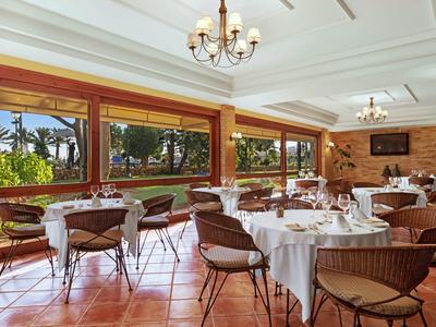 Světlá jídelna s velkými okny a elegantně prostřenými stoly.