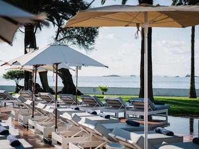 Lehátka pod slunečníky s výhledem na klidné moře a ostrovy na obzoru.