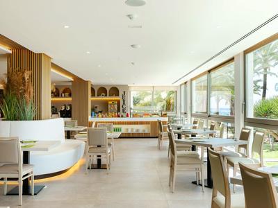 Moderní hotelová jídelna s velkými okny a elegantním nábytkem.