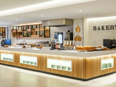 Moderní osvětlený pult s pečivem v světlé a prostorné pekárně.