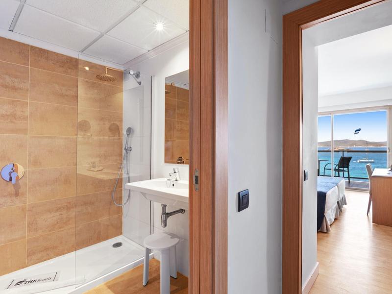 Moderní koupelna se sprchou a světlý pokoj s balkonem a výhledem na moře.