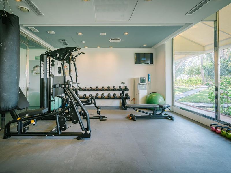Světelná posilovna s moderním vybavením a velkými okny s výhledem na přírodu.