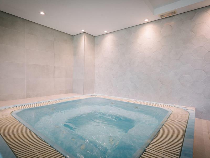 Moderní vnitřní vířivka s hladkými betonovými stěnami a jemným osvětlením.