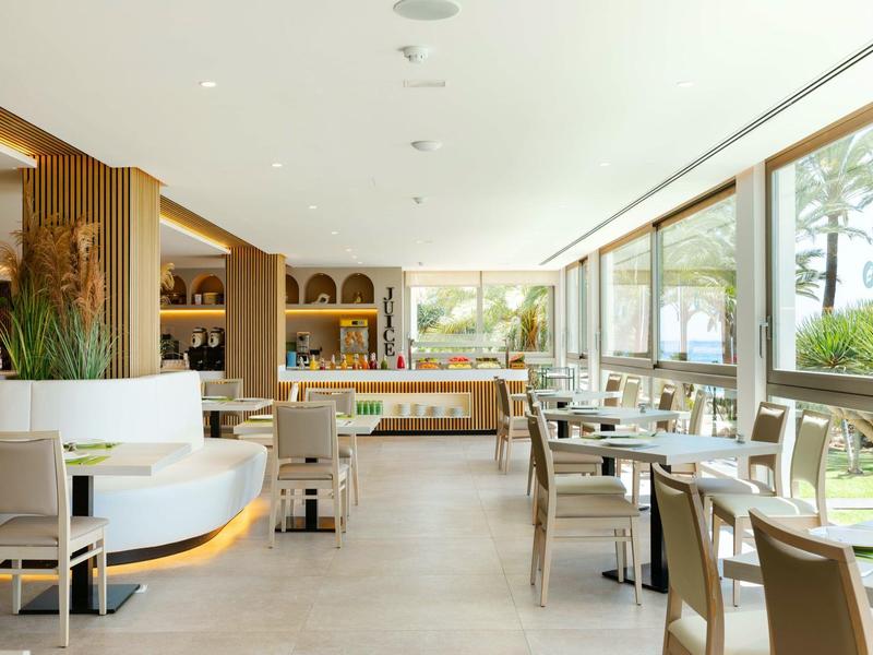 Moderní hotelová jídelna s velkými okny a elegantním nábytkem.