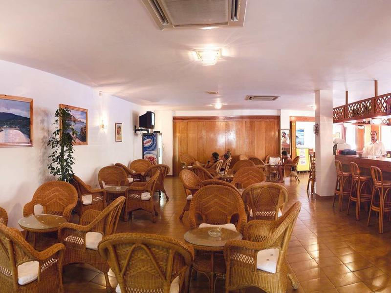Bright hotel dining area with wicker furniture and bar with stools