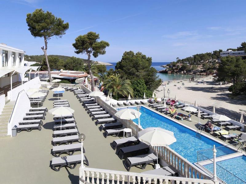 Piscine d'hôtel avec chaises longues et vue sur la mer par une journée ensoleillée