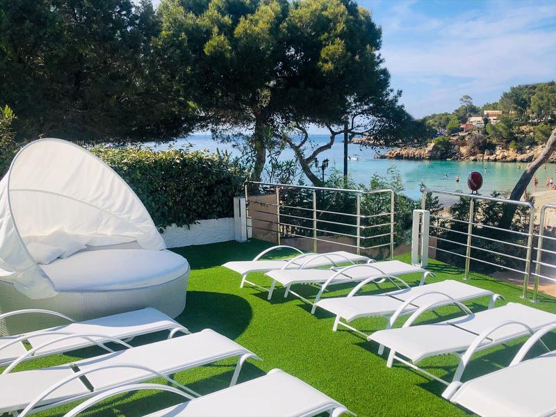 Terrasse avec chaises longues et sièges rembourrés au bord de l'eau avec des arbres en arrière-plan