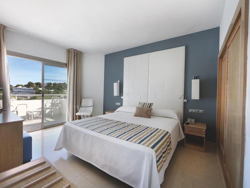 Chambre d'hôtel moderne avec lit à baldaquin, balcon et vue sur la mer dans un design clair et simple.