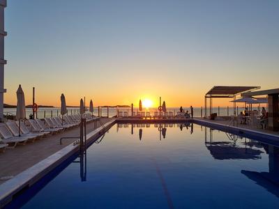 Infinity-Pool auf einer Dachterrasse mit Sonnenuntergang und Liegestühlen