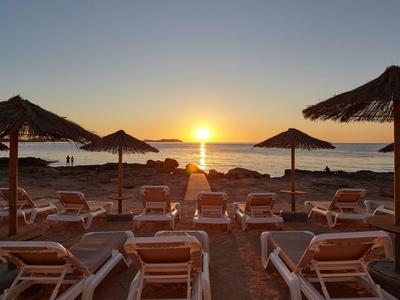 Zachód słońca na plaży z pustymi leżakami i parasolami ze słomy