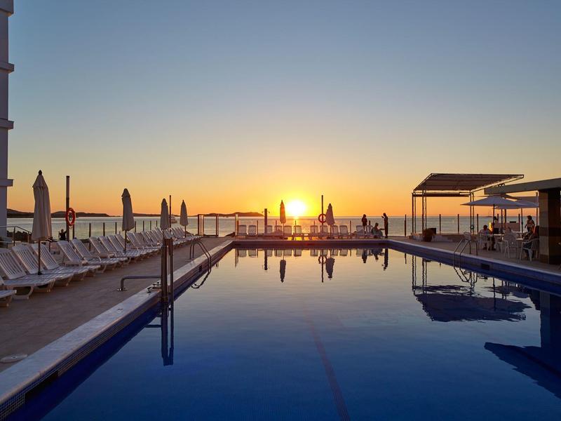 Basen hotelowy z leżakami podczas zachodu słońca i klarowną odbijającą wodą