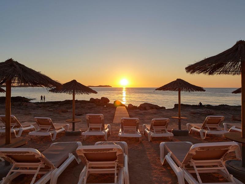 Zachód słońca na plaży z pustymi leżakami i parasolami ze słomy