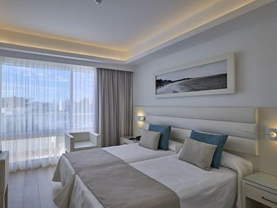 Bright hotel room with two single beds, modern decor, and large window with mountain view.