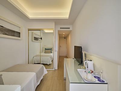 Modern hotel room with bed, mirrored wardrobe, and TV on dresser.