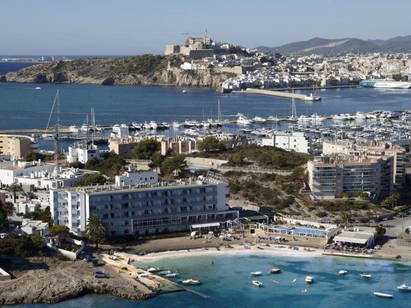 View of a coastal town with harbor, white buildings, and a castle on a hill.