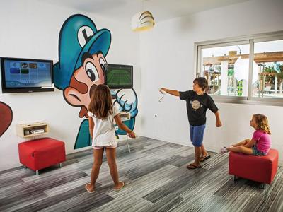 Kinder spielen in einem Raum mit Wandkunstfiguren und Sitzecken.