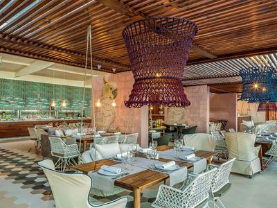 Modern eingerichtetes Restaurant mit Holzdach, geflochtenen Lampen und weißen Stühlen.