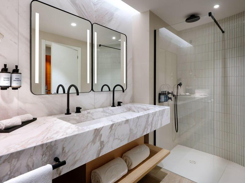 Bagno elegante con doppio lavabo in marmo e doccia a filo pavimento moderna.