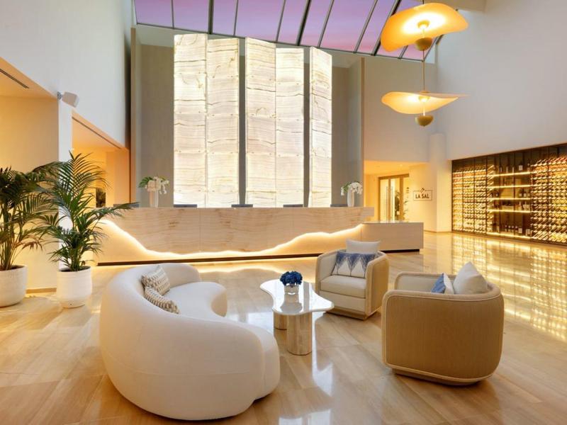 Salotto luminoso con poltrone di design e grandi finestre in un ambiente alberghiero moderno.