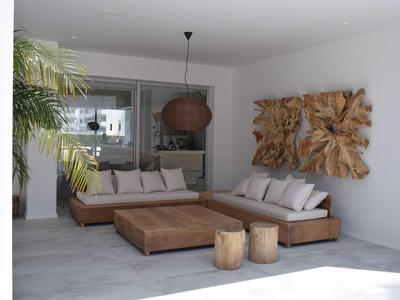 Moderner Wohnzimmerbereich mit großem Ecksofa, Holztisch, dekorativer Wandkunst und Pflanze am Fenster.