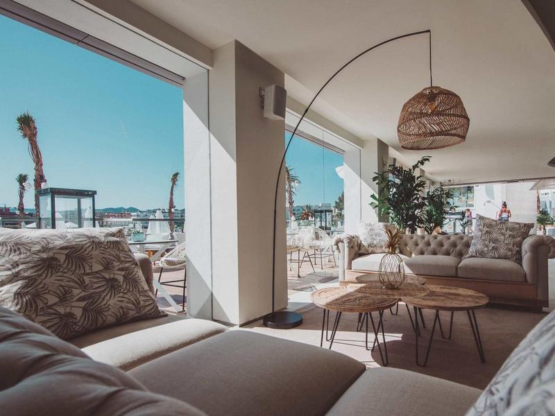 Lounge dell'hotel luminosa con divani accoglienti, tavoli rotondi e vista sull'area esterna.