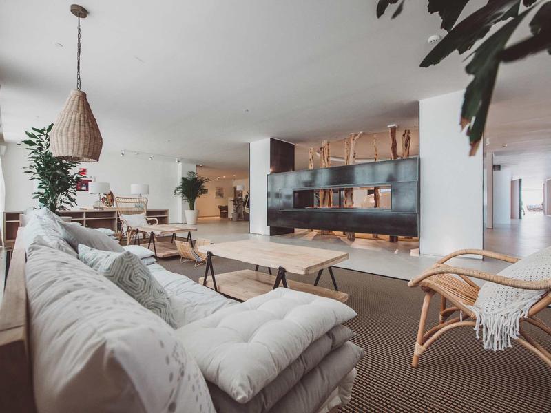 Soggiorno moderno con divani accoglienti, scaffali in legno e tappeti morbidi in uno spazio aperto.