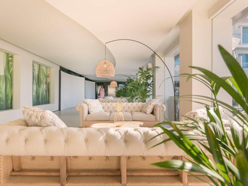 Soggiorno moderno e luminoso con divani comodi, grandi finestre e piante verdi.